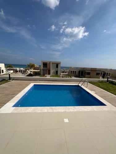 马斯喀特The Beach House的一个大型的游泳池,背景是大海