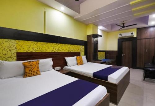 坎普尔Hotel Aditya Palace By WB Inn的黄色和蓝色的客房内的两张床