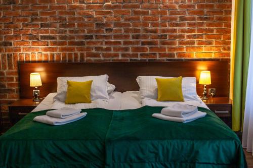 格但斯克Hotel Artus - Old Town的卧室配有一张带绿床单和枕头的大床。