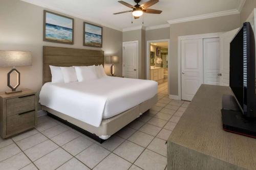奥兰治比奇Palm Beach Resort Orange Beach a Ramada by Wyndham的卧室配有一张白色大床和电视。