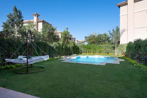 开罗Kattameya dunes 4 master bedrooms villa的庭院内的秋千,设有游泳池