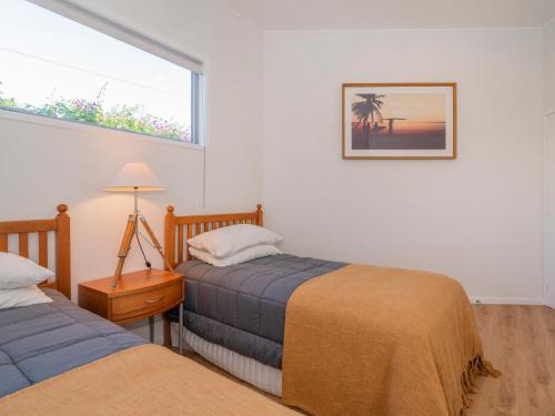 旺阿马塔Coast Awhile - Whangamata Holiday Home的一间卧室设有两张床和窗户。