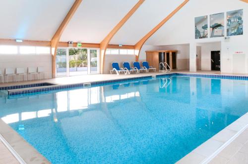 帕兹托Trevone House with Hot Tub on Retallack Resort的大楼内带蓝色椅子的大型游泳池