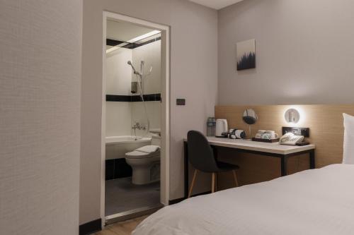 台北Hubhotel Benqiao Inn Far Eastern Branch的酒店客房设有一张床、一张书桌和一个卫生间