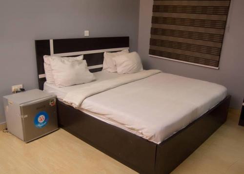 拉各斯BOSS HOTELS & SUITES*****的一间卧室配有一张带白色床单的大床