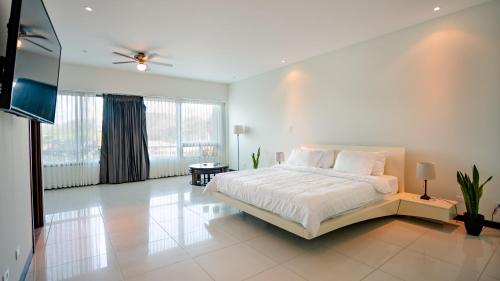 普拉亚埃尔莫萨CasaGuana的白色卧室配有床和平面电视