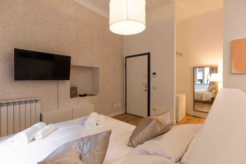 米兰Divini Gae Aulenti的卧室配有白色的床和平面电视。