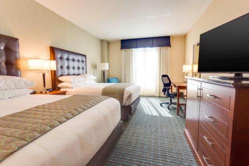 盖恩斯维尔Drury Inn & Suites Gainesville的酒店客房设有两张床和一台平面电视。