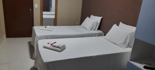 卡姆布库Pousada Tartaruga的两张位于酒店客房的床,配有毛巾