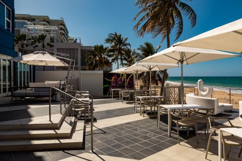 圣胡安The Tryst Beachfront Hotel的一个带桌子和遮阳伞的庭院和海滩