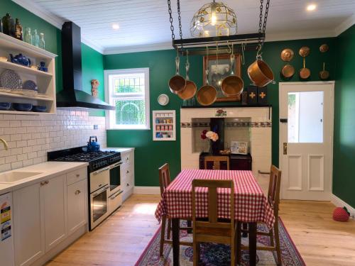 皇后镇The Ferry Bed & Breakfast的带绿色墙壁和桌椅的厨房