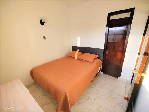 阿里卡La mejor ubicación de Arica的一间卧室配有带橙色床单的床和一扇门