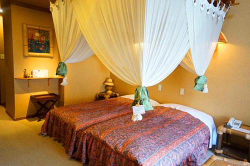 嬬恋村埃斯蒂万特俱乐部旅馆的一间卧室配有一张带天蓬和窗帘的床
