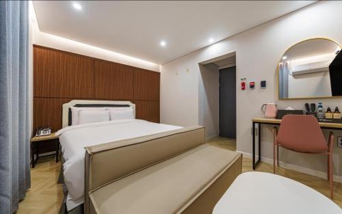 春川Number25 Hotel Namchuncheon的一间卧室配有一张床、一张书桌和一面镜子