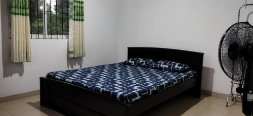 AthurugiriyaPeaceful Holiday Home的一间卧室配有一张带蓝色棉被的床和风扇
