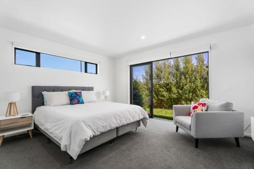 瓦纳卡Northlake Hideaway - Wanaka Holiday Home的卧室配有床、椅子和窗户。