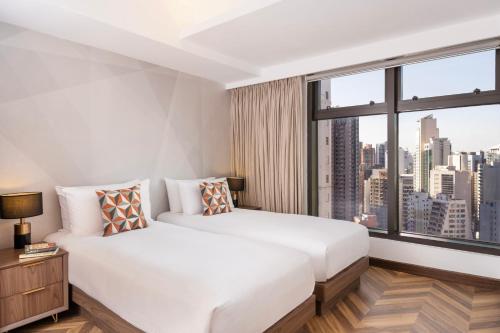 香港中环莎玛服务式公寓的卧室设有白色的床和大窗户