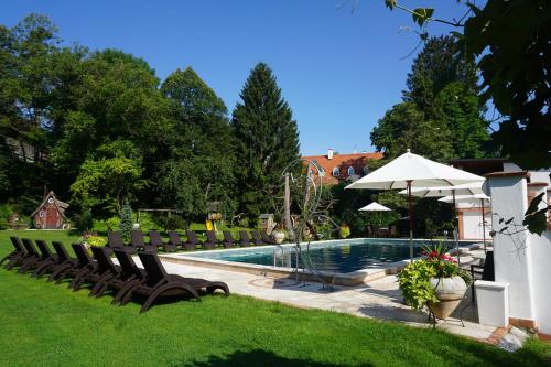 Eibiswald克鲁普菲客乐花园酒店的庭院内的游泳池配有椅子和遮阳伞