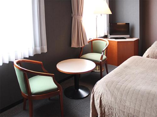 平冢市HOTEL LiVEMAX BUDGET Hiratsuka Ekimae的酒店客房带两把椅子、一张桌子和一张床