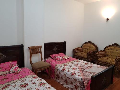法尤姆Azzam Guest House 2 families only的一间卧室配有两张床和两把椅子