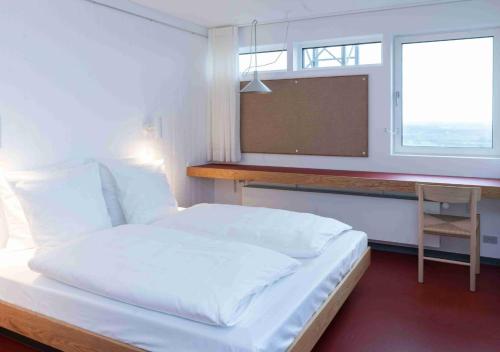 海宁Højhuset Kulturhotel的一间卧室配有一张带书桌的床和窗户。
