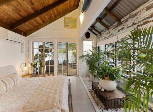 努萨角Sunset on Noosa Chalet的一间卧室,配有一张床和盆栽植物