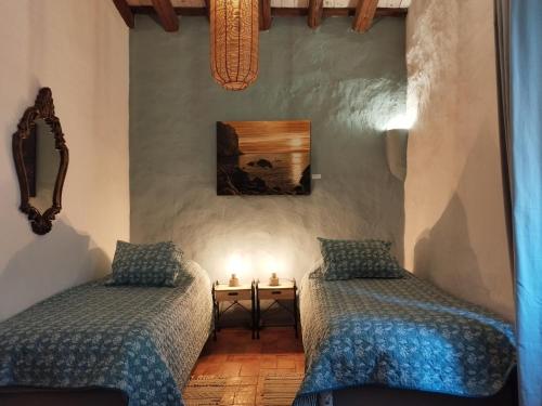 SobrestanyMas Del Llop Blanc - Dog friendly Hostal Rural - B&B的一间卧室设有两张床和一张带蜡烛的桌子。