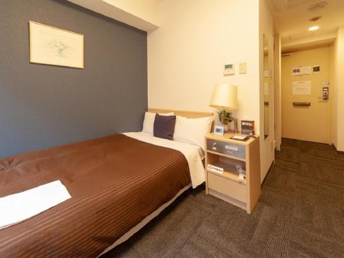 东京HOTEL LiVEMAX BUDGET Shinbashi的酒店客房设有一张大床和一盏灯。