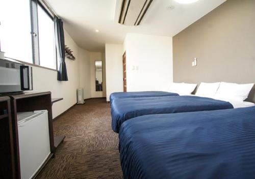 沼田HOTEL LiVEMAX BUDGET Gunma Numata的酒店客房设有两张床和一台平面电视。