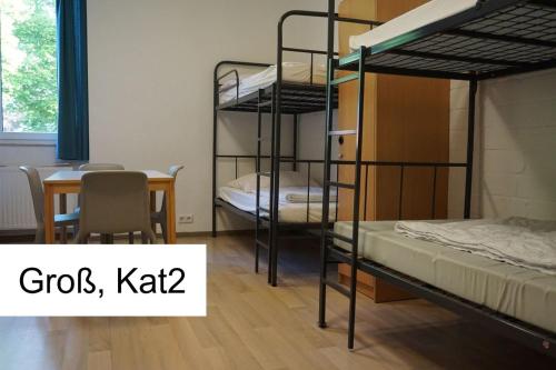 新明斯特Kiek in AöR Jugendherberge & Hostel的客房设有三张双层床、一张桌子和一张桌子。