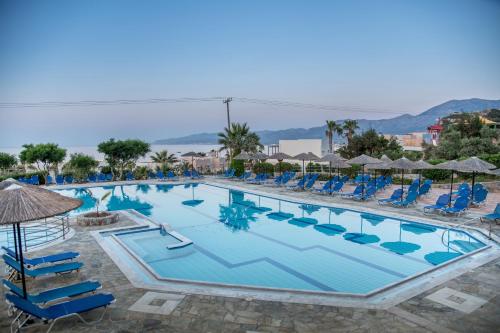赫索尼索斯塞米勒米斯村酒店的一个带蓝色椅子和遮阳伞的大型游泳池