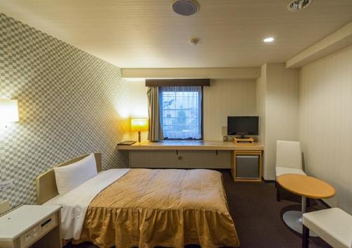 甲斐市HOTEL LiVEMAX Kofu的一间卧室配有一张床和一张带电脑的书桌