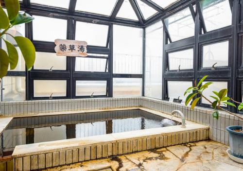 甲斐市HOTEL LiVEMAX Kofu的温室中的浴缸,有池水
