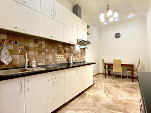 基辅Чарівна, простора квартира в 2хв від МВЦ, Лівобережна的厨房配有白色橱柜和桌子