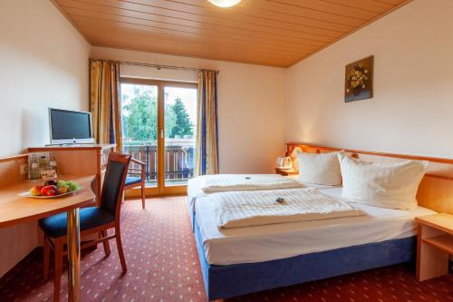 Wächtersbach祖尔奎勒兰德酒店的酒店客房配有一张床、一张书桌和一台电视。