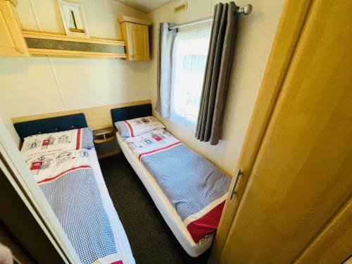 尚克林3 Bedroom Caravan KG37, Dog Friendly, Shanklin, Isle of Wight的小型客房 - 带2张床和窗户