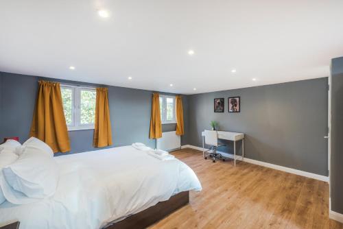 伦敦Spacious 4 bed house near Greenwich的卧室配有一张白色大床和一张书桌