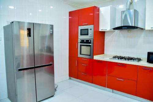 拉各斯Beautiful Town House的厨房配有红色橱柜和不锈钢冰箱