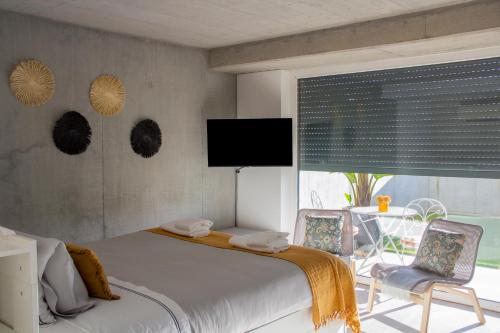 阿威罗Casa das Falcoeiras - Estúdio com terraço privado的一间卧室配有一张床、两把椅子和一台电视