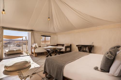 El KariaOxygen Lodge Agafay的一间卧室配有一张床,客厅配有桌子