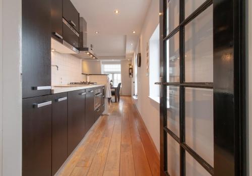阿尔克马尔ApartHotel Trendy by Urban Home Stay的厨房配有黑色橱柜和木地板