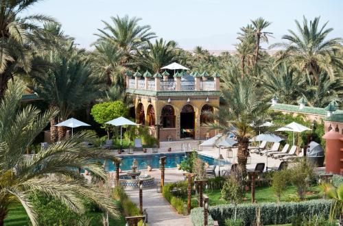 瓦尔扎扎特OZ Palace Ouarzazate & SPA的一个带游泳池和棕榈树的度假村