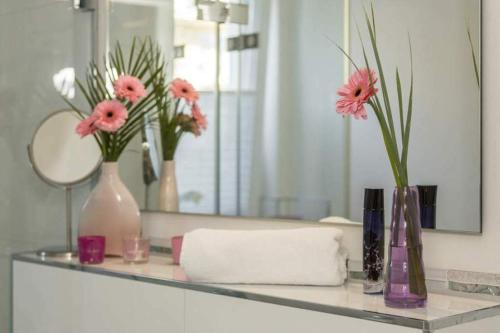 沙博伊茨Ferienwohnung Auszeit的浴室的柜台在镜子上摆放着花瓶和鲜花