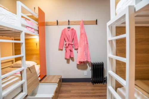 旧金山阿姆斯特丹旅舍的一间小卧室,配有双层床和粉红色的衣服