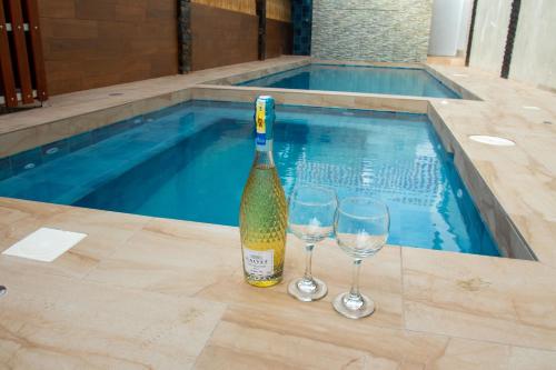 阿扬格HOTEL SEAHORSE AYANGUE的游泳池旁的一瓶香槟和两杯酒
