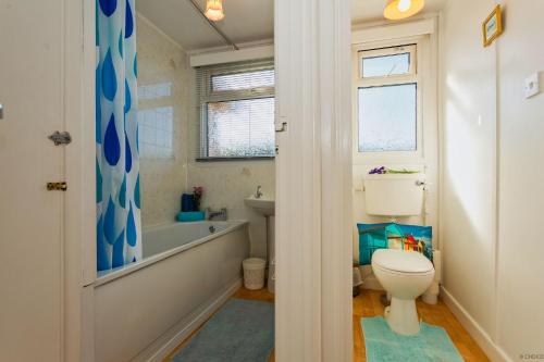 克罗伊德CROYDE SEA BREEZE 3 Bedrooms的浴室配有卫生间、浴缸和水槽。