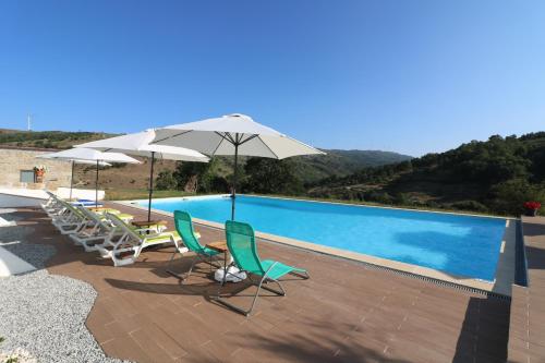 Quinta da Alqueidosa - Casa de Campo的游泳池旁设有椅子和遮阳伞