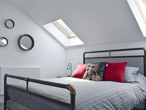 利德尼Perivale Lodge的一间卧室配有一张带红色枕头和镜子的床