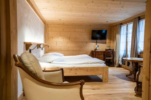 格施塔德罗斯黎酒店的一间卧室配有一张床、一把椅子和电视