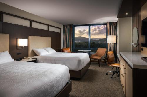 萨拉曼卡Seneca Allegany Resort & Casino的酒店客房带两张床和一张桌子以及椅子。